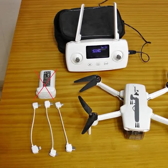 White mini quadcopter drone with controller and charging cables