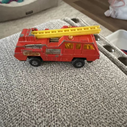 Red diecast fire pumper truck with yellow ladder and detailed front grille