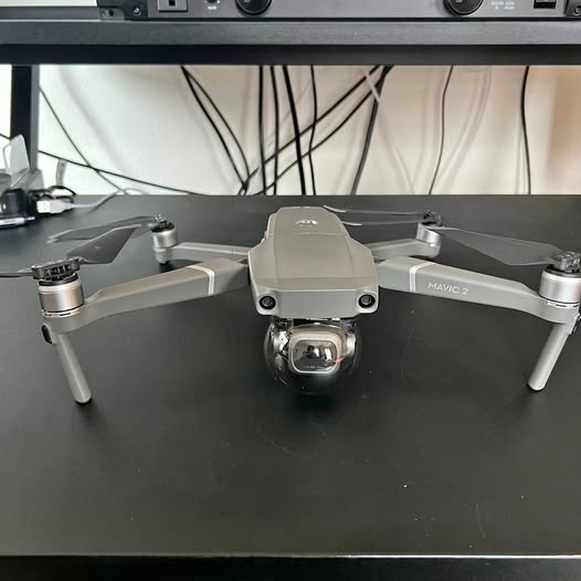 Gray foldable quadcopter drone with front camera and four propeller arms