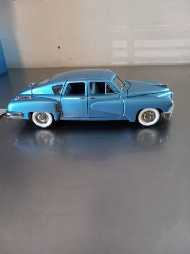 Blue 1948 Tucker 4dr diecast car model, front side view, whitewall tires