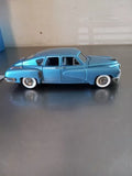 Blue 1948 Tucker 4dr diecast car model, front side view, whitewall tires