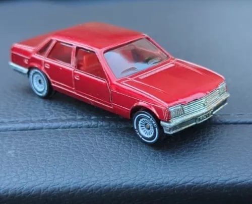Red diecast sedan model car with chrome grille and whitewall tires