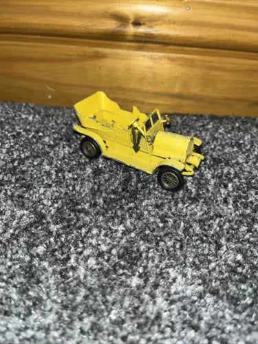 Yellow vintage diecast model car on gray textured surface