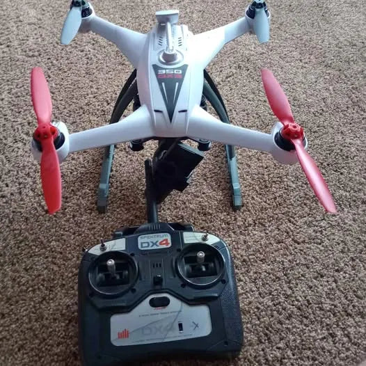 White quadcopter drone with four propellers and DX4 remote controller