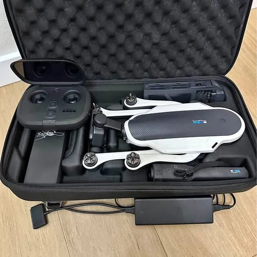 Hard-shell drone carry case with controller and folded drone, open top compartment