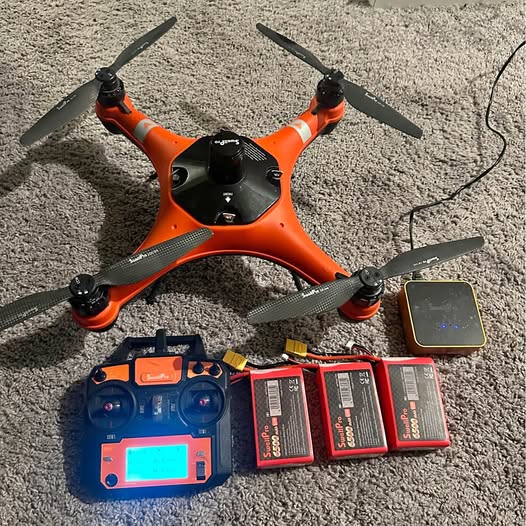 Orange quadcopter drone with four propellers and remote controller with screen