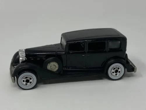 Vintage black diecast toy car, classic Packard-style sedan body, side view