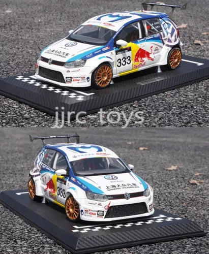 White Volkswagen racing diecast car model with blue stripes, orange wheels, on black base