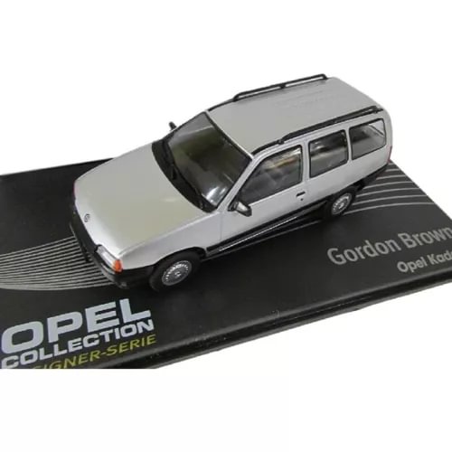 Light gray diecast station wagon model car with black windows, on branded display base.