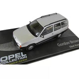 Light gray diecast station wagon model car with black windows, on branded display base.