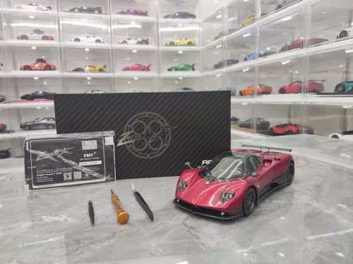 Red diecast sports car model with display box and accessory parts