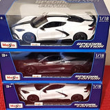 Diecast metal car models in retail boxes, one white and one dark red