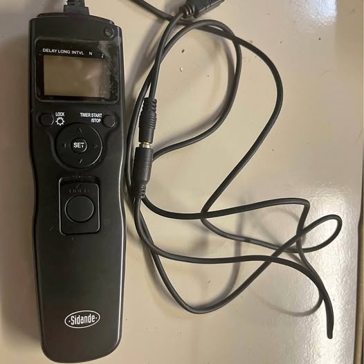 Black wireless DSLR shutter remote with LCD screen and control buttons, tethered cable