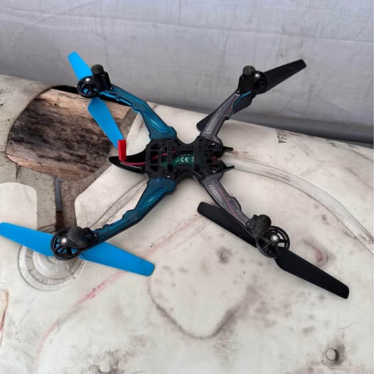Blue quadcopter drone with four propeller arms, black frame