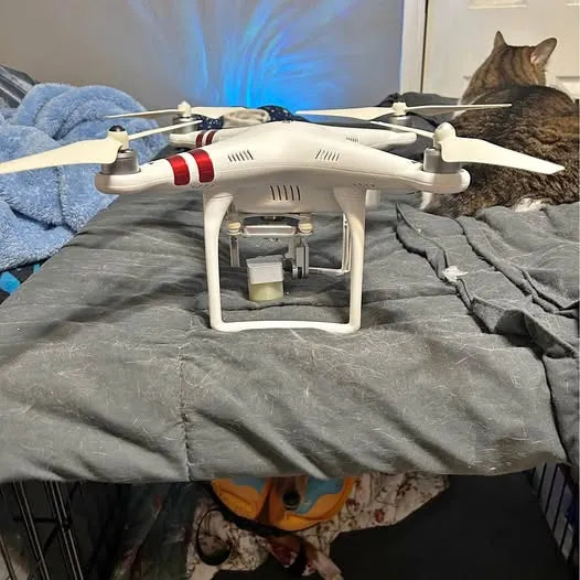 White quadcopter drone with red stripe, four propellers.