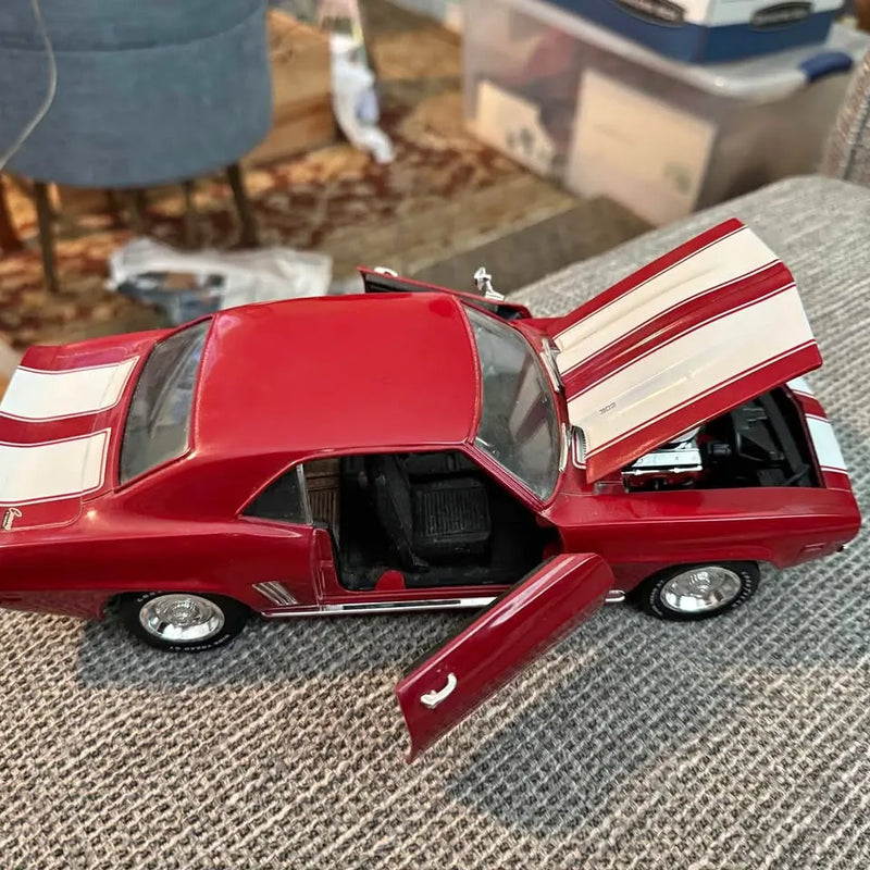 Red diecast 1969 Camaro model with white racing stripes, hood open, detailed interior
