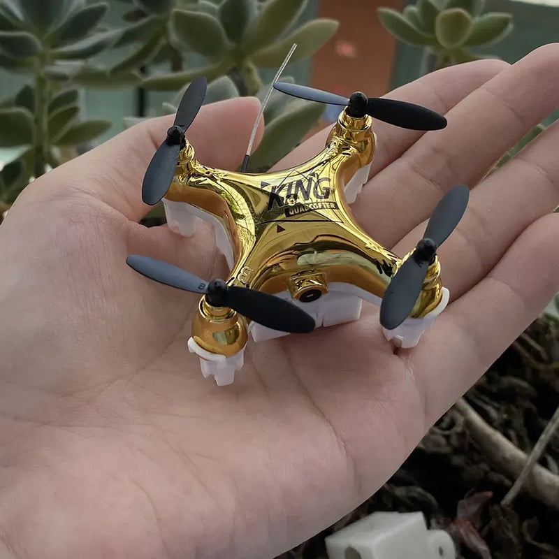 Mini quadcopter drone with golden body and blue propellers, held in a hand