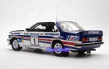 Diecast model rally car, white with blue and red stripes, black roof, front three-quarter