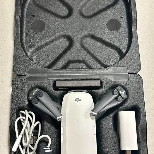 White DJI drone in open hard case with folded prop arms and battery