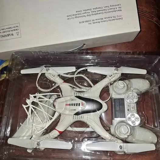 White quadcopter drone with prop guards in clear plastic retail box tray