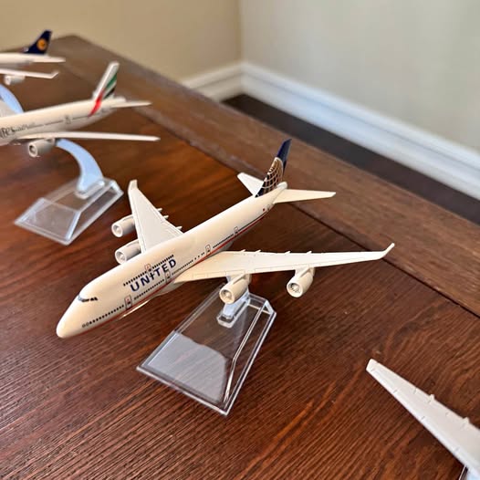 Diecast airplane model with landing gear raised, mounted on clear display stand
