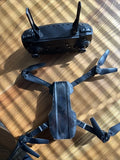 Black drone with four propellers, folded arms and front camera pod