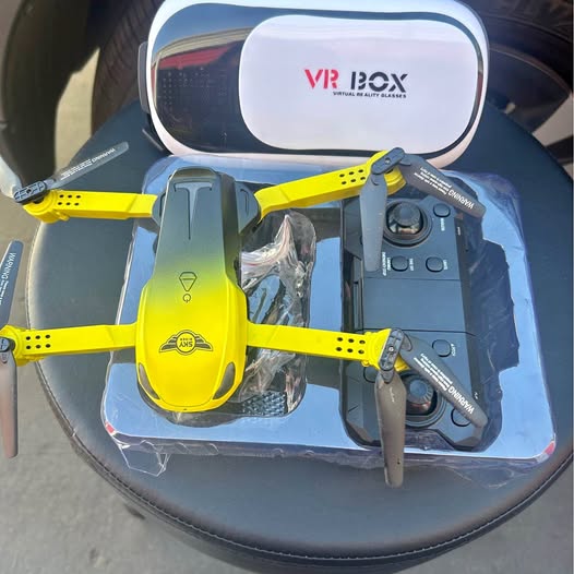 Yellow quadcopter drone with four rotors, shown with VR headset in packaging
