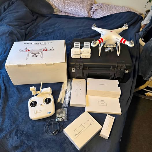 White quadcopter drone with remote controller, batteries, charger, and manuals
