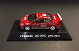 Red diecast rally car model with Peugeot 307 WRC styling, on display base.