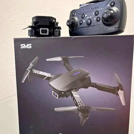Grey quadcopter drone with camera gimbal and three-blade propellers, side view.
