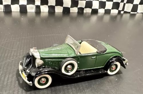 Dark green diecast roadster model car with open hood and raised windshield