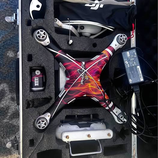 Quadcopter drone with four propellers in open hard case, gray body and cables