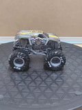 1:64 diecast monster truck, gray with dark tires and detailed engine grille, front view