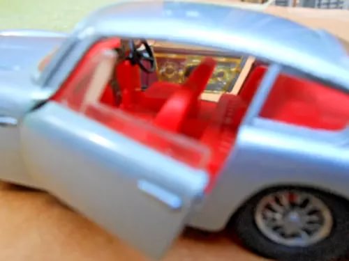 Light blue diecast model car with red interior, doors open, front wheel visible