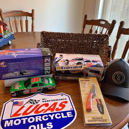 Diecast toy cars and motorcycle in boxes with racing wheels, helmet, and accessories