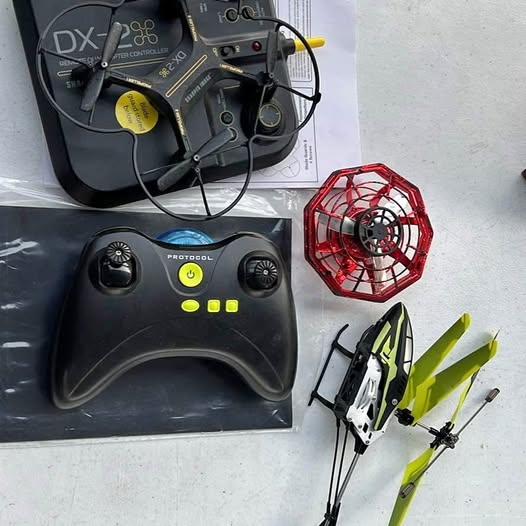 RC drone controller with drone and red prop guard, dark gray with green accents
