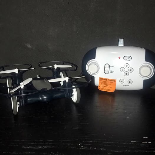 White remote control with screen and buttons beside black quadcopter drone with propellers
