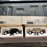 Diecast car model in box, black car with whitewall tires and red car in packaging