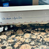 Diecast tractor trailer replica with white trailer, blue slogan, red stripe accents.
