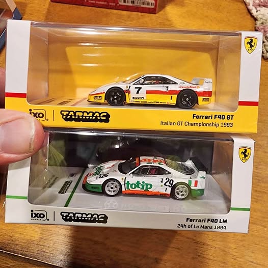 Boxed diecast Ferrari race car model display, yellow and white/green versions