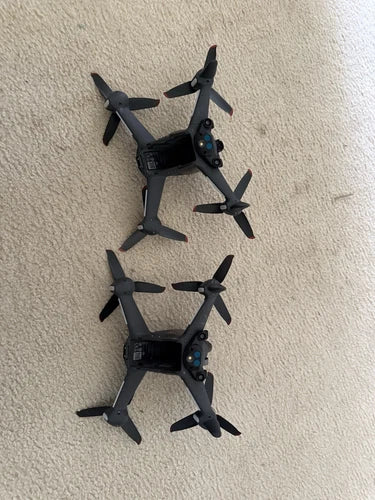 Two quadcopter drones with four foldable propellers each, compact black body