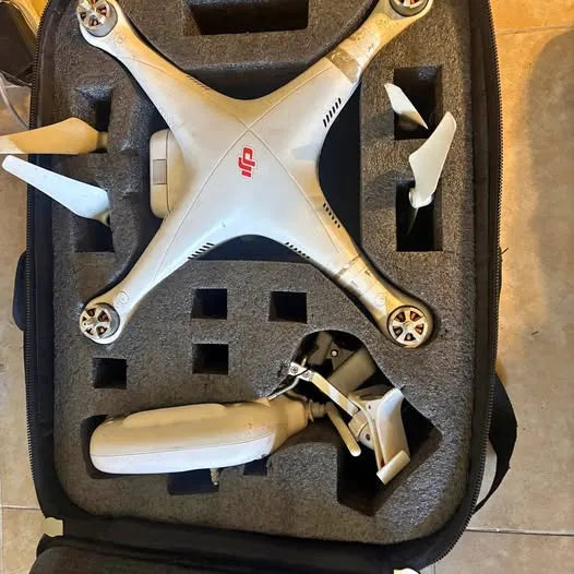 White quadcopter drone with four blades, placed in gray foam carry case