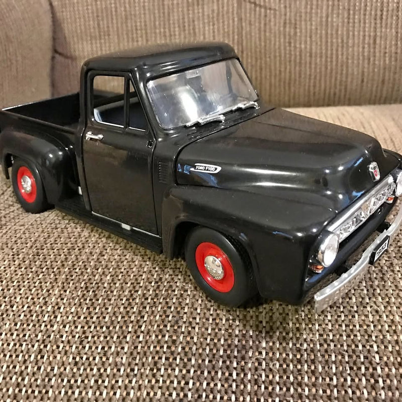 Black diecast pickup truck model with chrome grille and red wheels