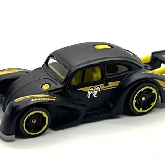 Black die-cast race car with yellow wheels, window decals, and hood detail