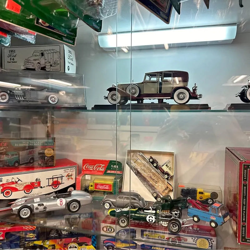 Diecast model cars in glass display case, vintage race cars on shelves