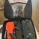 Foldable quadcopter case with orange drone body and gray dual-stick remote controller