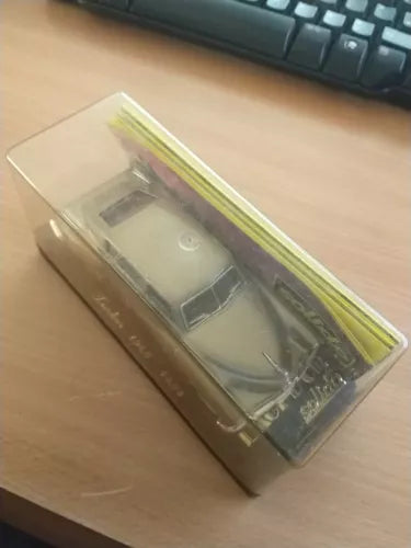 Diecast model car in clear blister packaging, gray body with wheels visible.