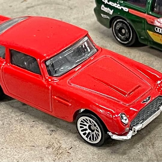 Red die-cast sports car, front three-quarter view, chrome grille and wheels