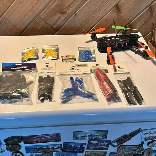 Multirotor drone with orange arms and boxed spare parts in plastic bags