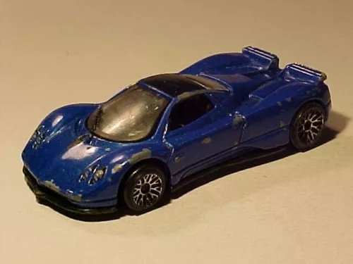 Blue diecast sports car model with black wheels, rear spoiler, front view.